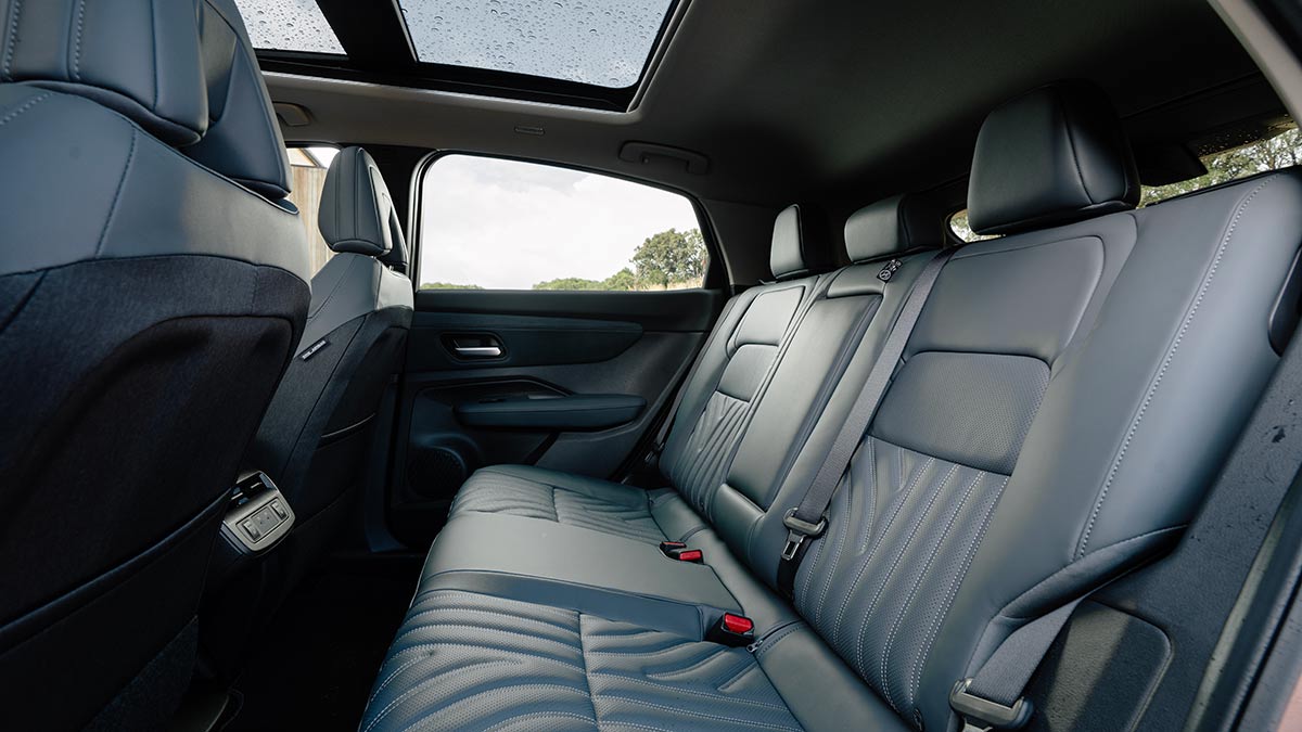 Rear seat area and panoramic glass roof in Nissan Ariya Evolve electric SUV.