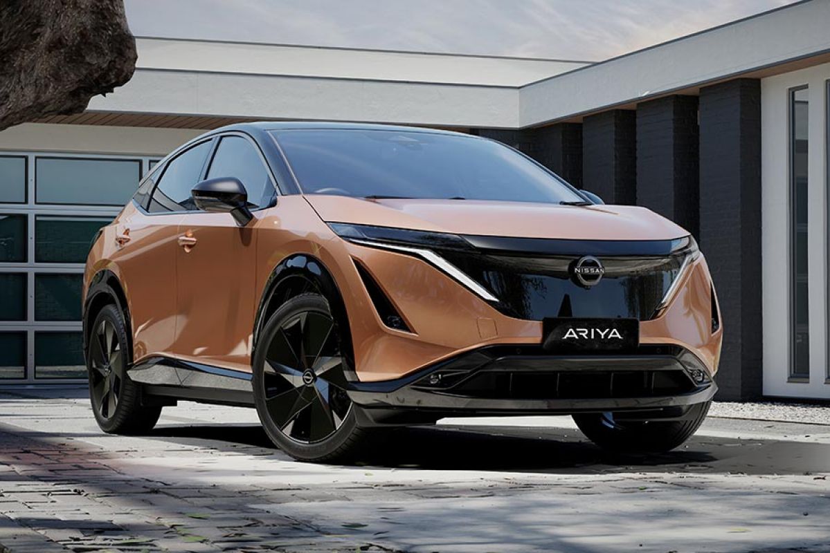 Copper-coloured Nissan Ariya medium electric SUV in front of modern house