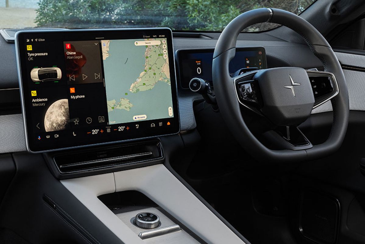 Interior of Polestar 4 prestige SUV at beachside showing large central touchscreen and steering wheel.