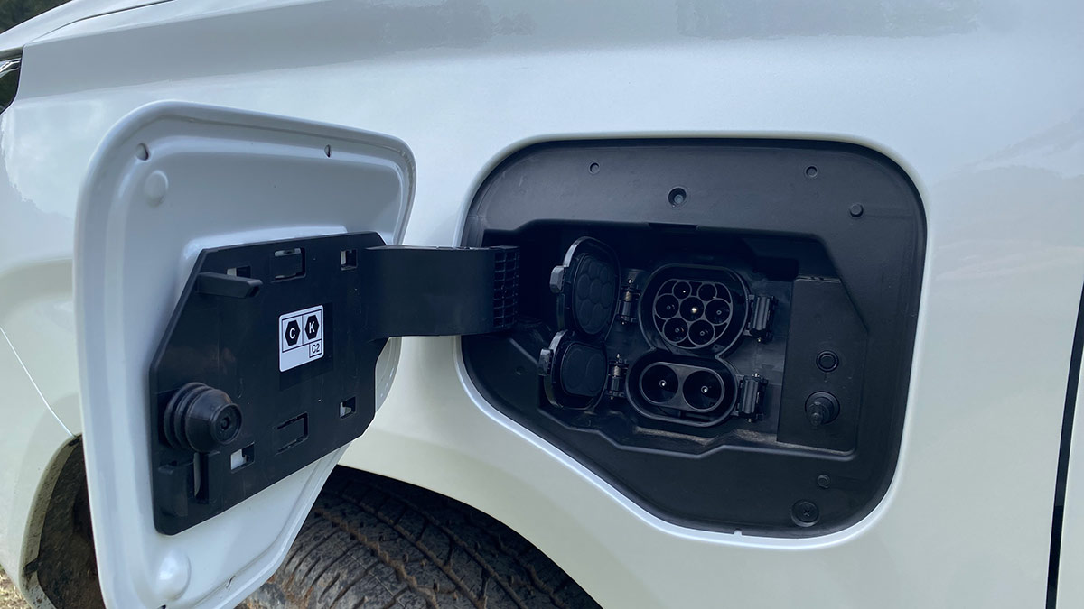 Open flap at front left quarter panel of Toyota HiLux BEV showing DC and AC charging ports.