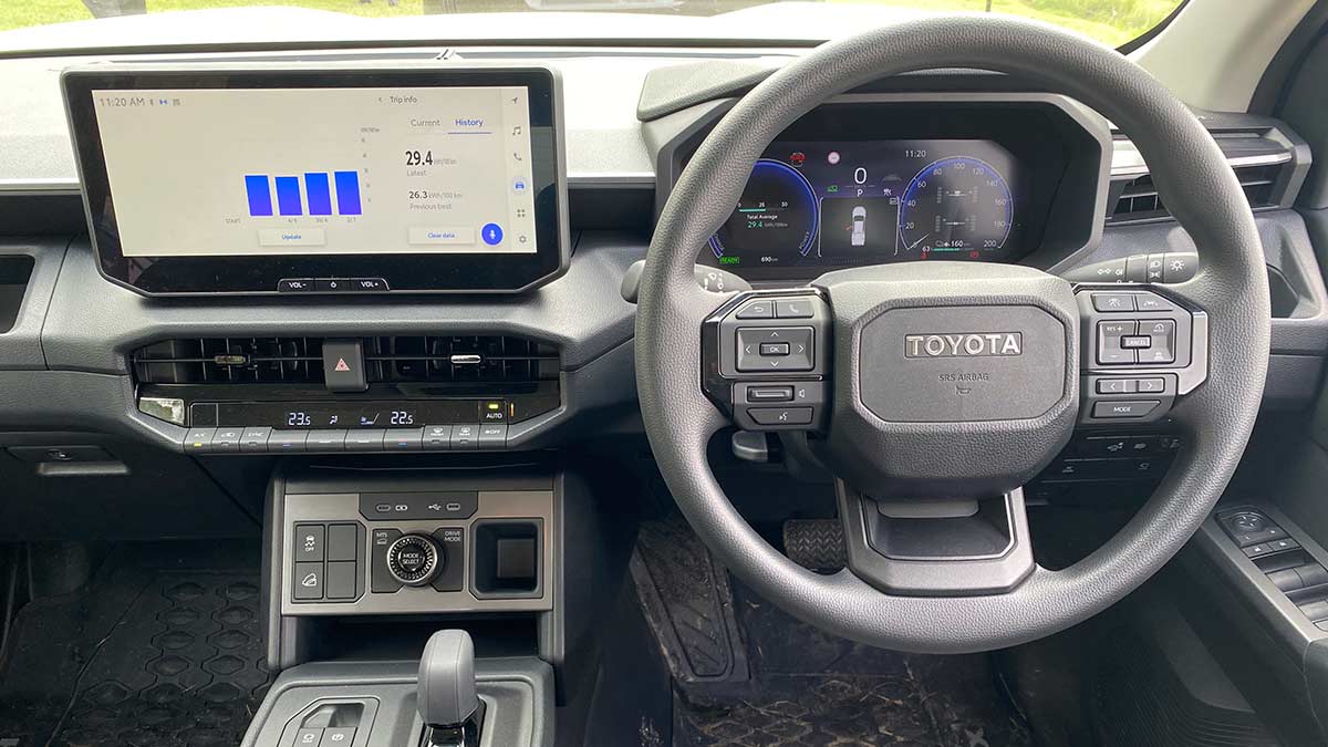 Toyota HiLux SR BEV dash with large digital instrument panel and touchscreen showing EV efficiency graph.