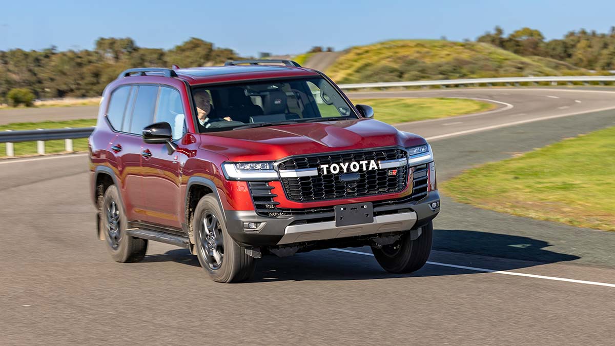 Red Toyota LandCruiser Hybrid on winding stretch of paved road at proving ground in Altona.