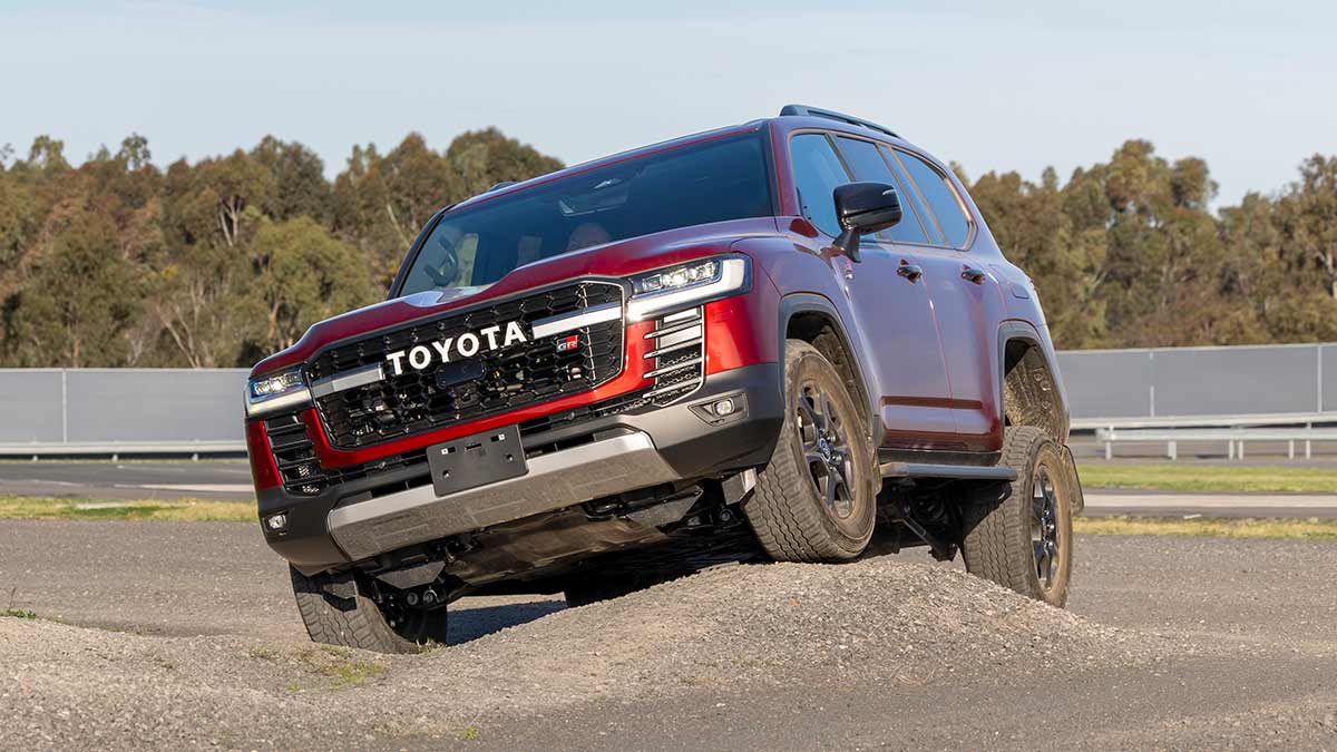 Red Toyota LandCruiser Hybrid driving across moguls at proving ground in Altona.