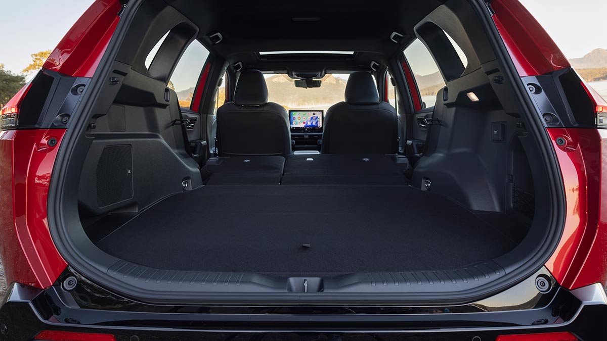 Tailgate open of red Toyota RAV4 GR Sport PHEV showing cargo area with rear seats folded down.