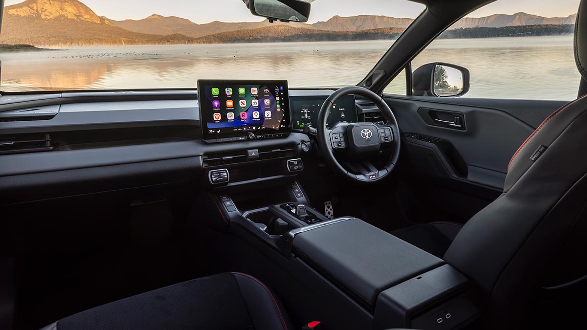Front compartment of Toyota RAV4 GR Sport PHEV with dark trim, red highlights, sports seats and dual digital screens.