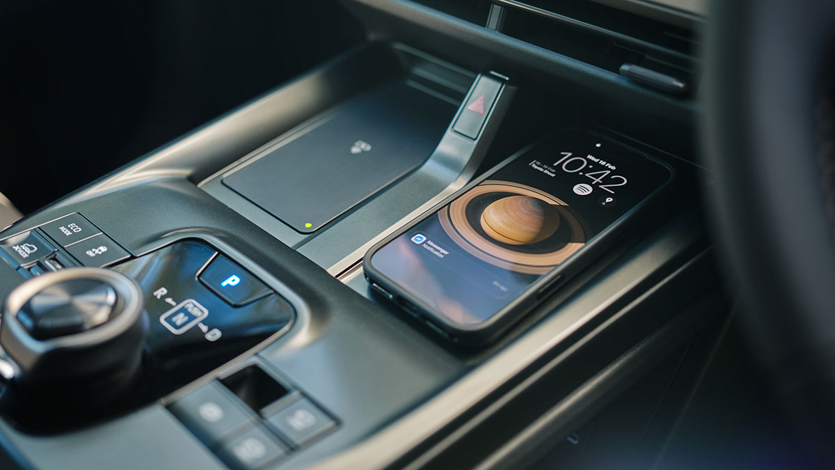 Centre console of Toyota bZ4X Touring SUV with mobile phone in one of two wireless chargers.