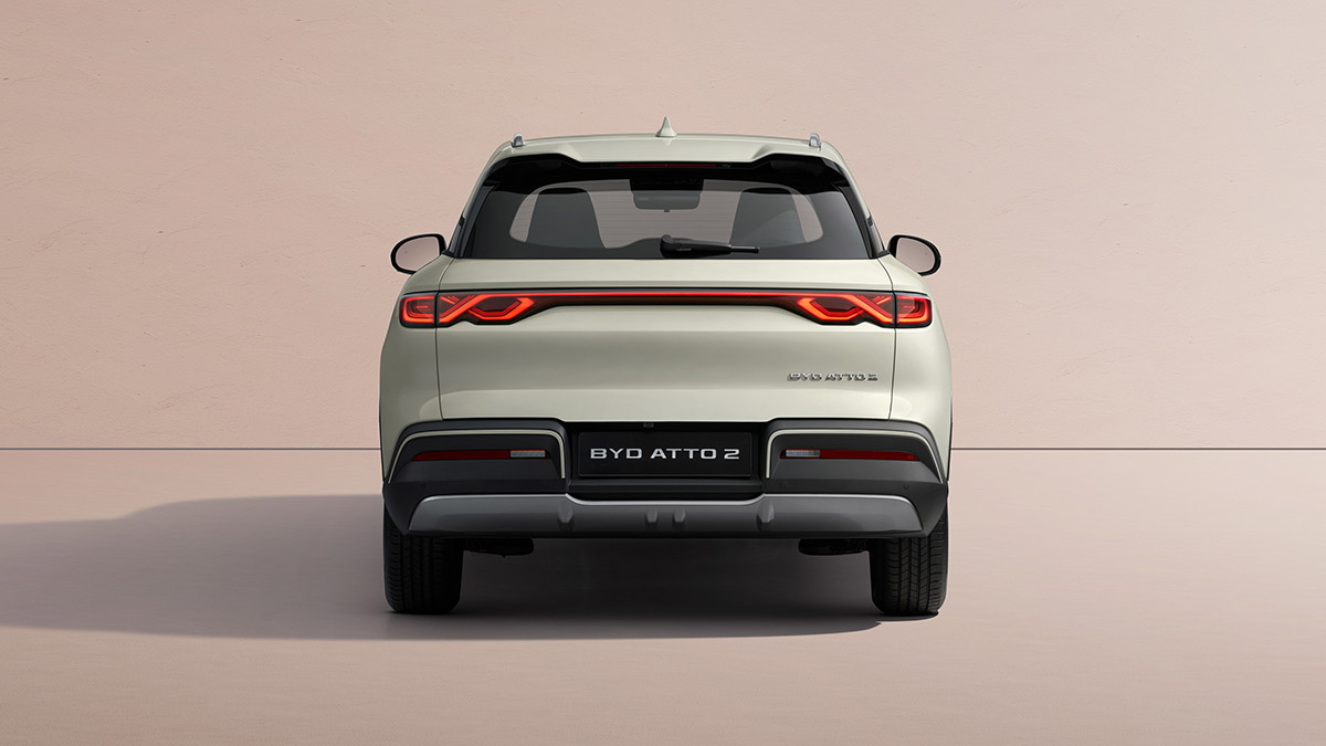 Rear studio shot of light grey BYD Atto 2 small electric SUV with pastel tan background