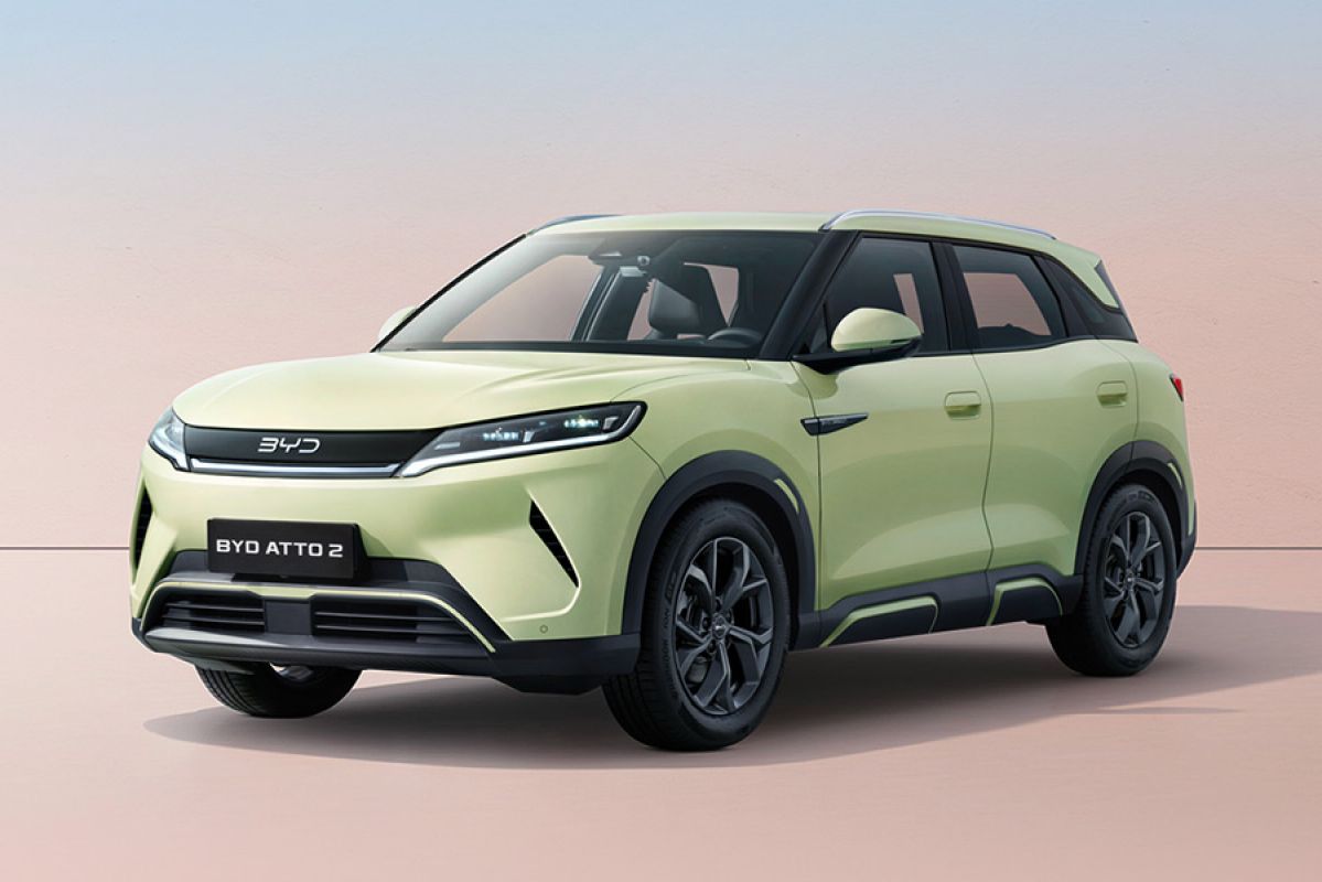 Front quarter studio shot of light green BYD Atto 2 small electric SUV with pastel tan background