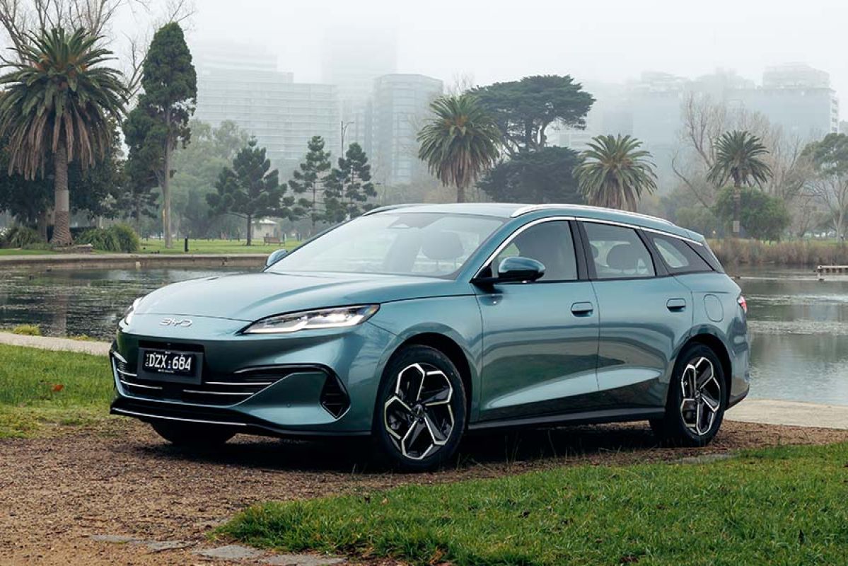 Sage green BYD Seal 6 Touring wagon parked at Albert Park Lake with misty Melbourne CBD skyline behind.