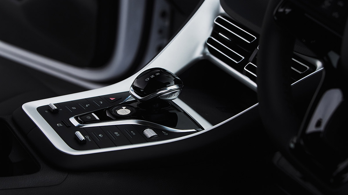 Transmission lever surrounded by buttons in BYD Sealion 5 SUV with gloss-black and metallic-look plastic trim.