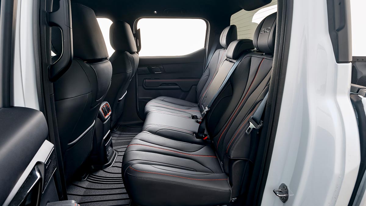 Rear seat area inside white BYD Shark 6 Performance ute with dark artificial leather trim.