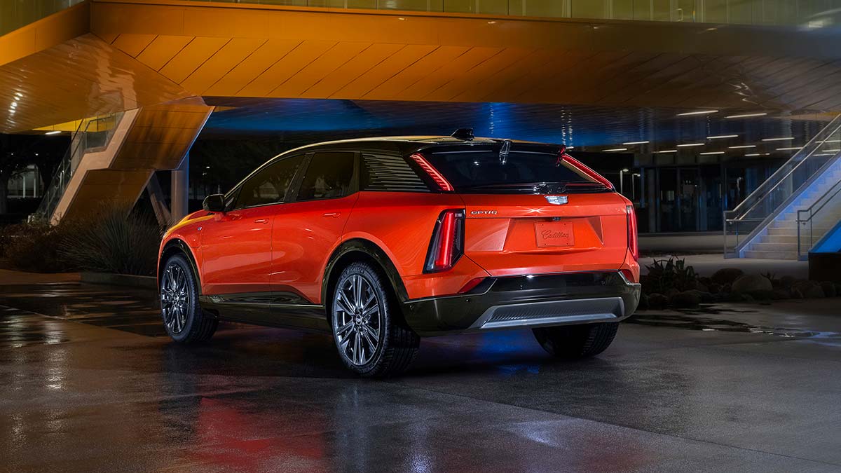 Rear shot of red Cadillac Optiq mid-size SUV in carpark outside modern office building