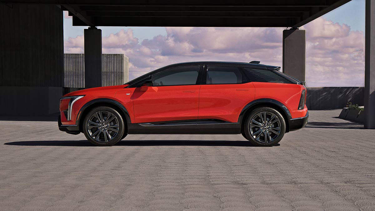 Side-on view of red Cadillac Optiq mid-size SUV on roof of office building