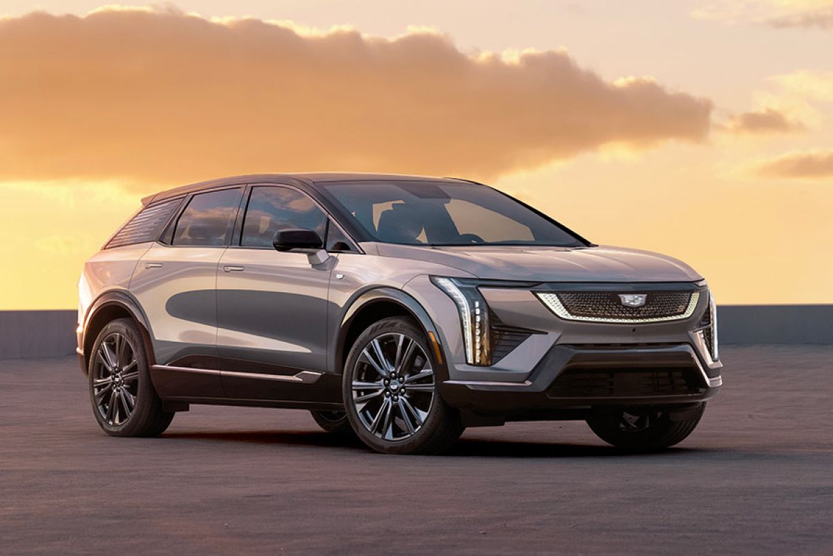 Silver Cadillac Optiq medium luxury SUV on rooftop car park at dusk with golden sky behind