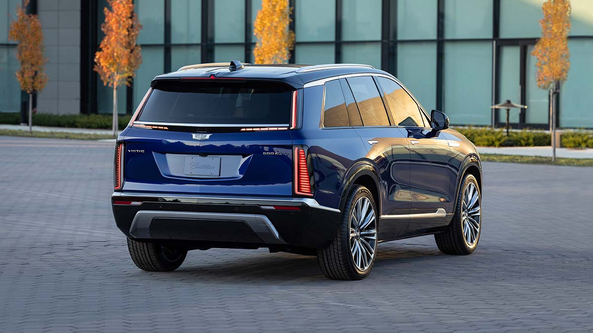 Rear view of blue Cadillac Vistiq three-row luxury SUV outside office building