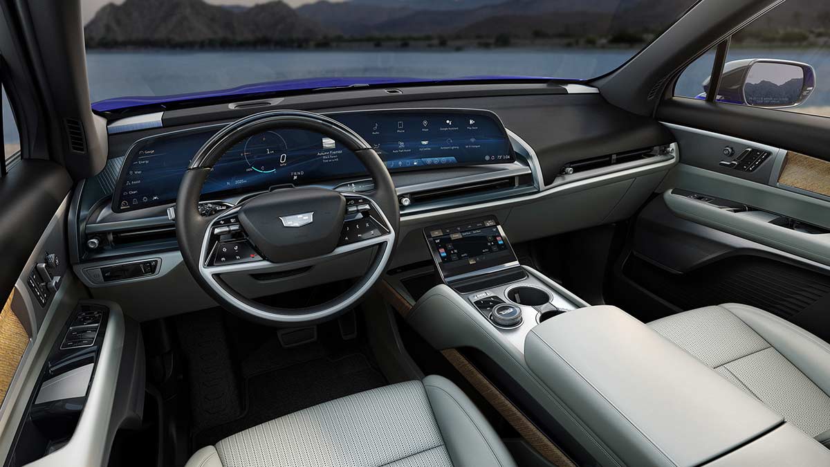 Front cockpit of Cadillac Vistiq SUV showing large 33-inch curved driver's display and white seat upholstery