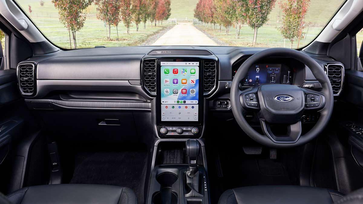 Cockpit of Ford Everest Active SUV with dual digital screens and dark trim on seats, steering wheel and dash.