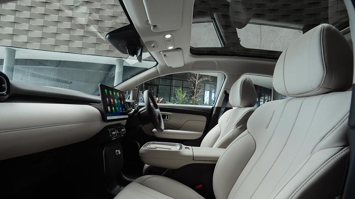 View of GAC Aion UT cockpit from front passenger’s door, showing cream trim, floating centre console, large touchscreen and sunroof.