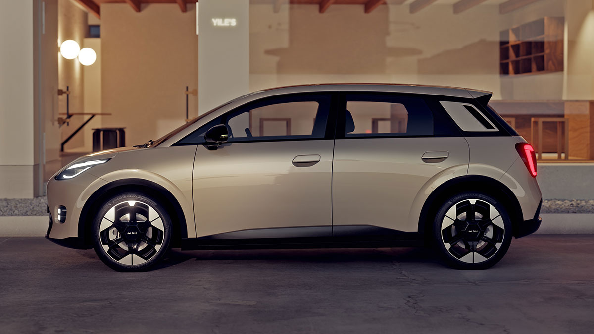 Side view of gold-coloured GAC Aion UT electric hatch parked outside luxury retail premises.