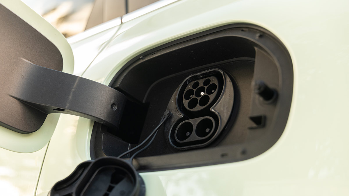 Charge flap open on light green Geely EX2 hatch showing AC and DC ports.