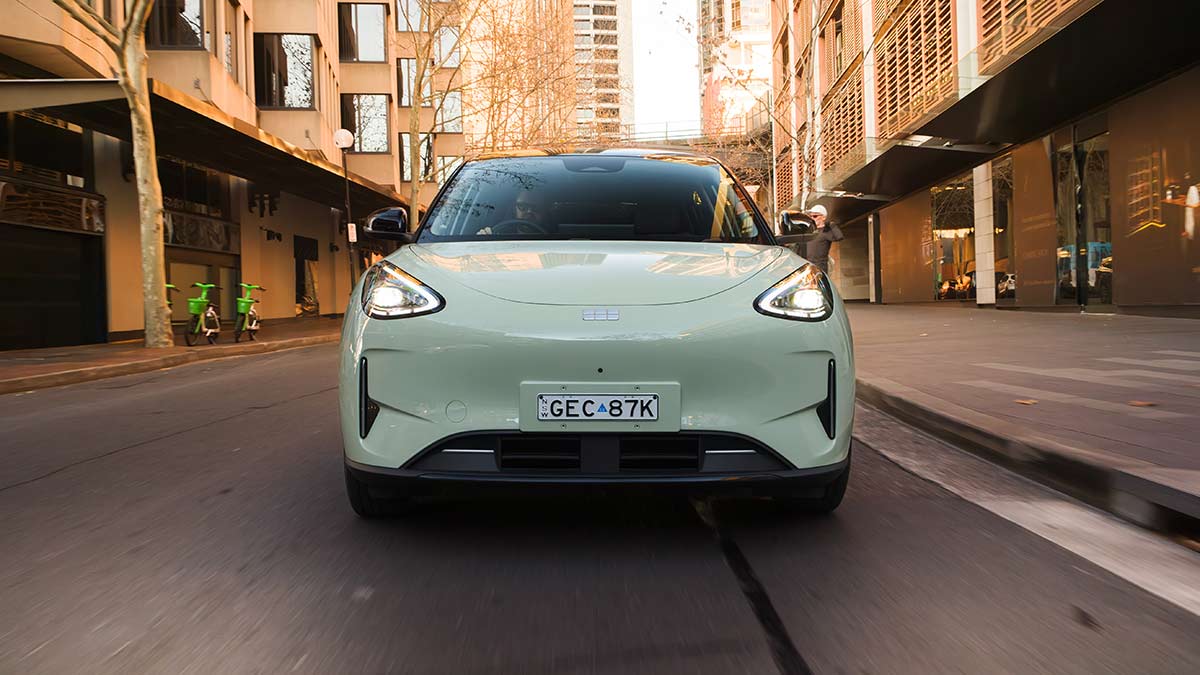 Front-on shot of light green Geely EX2 EV hatch on sunlit inner-city Sydney suburban street.