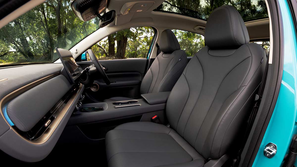 Front seats of GWM Ora 5 as seen from passenger's door, showing dark faux leather trim, lighter highlights and panoramic sunroof.