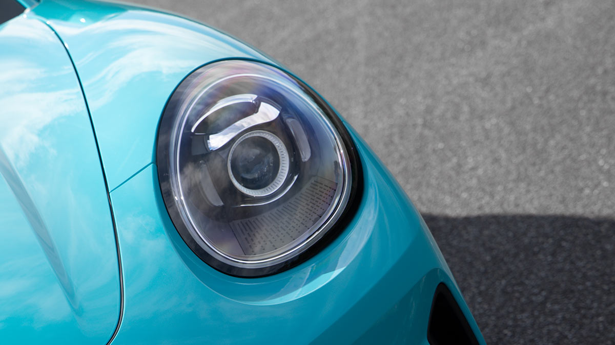 Close-up of round headlight on duck-egg blue GWM Ora 5 small electric SUV.