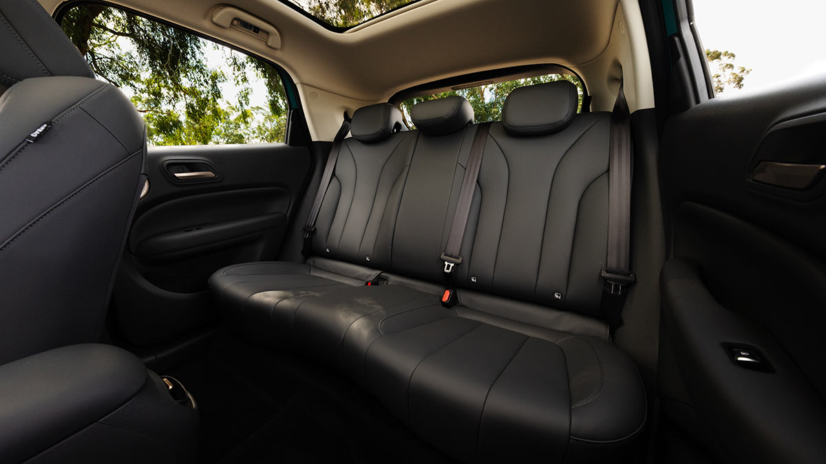 Rear seat of GWM Ora 5 small SUV with dark faux leather trim, beige headlining and panoramic sunroof.