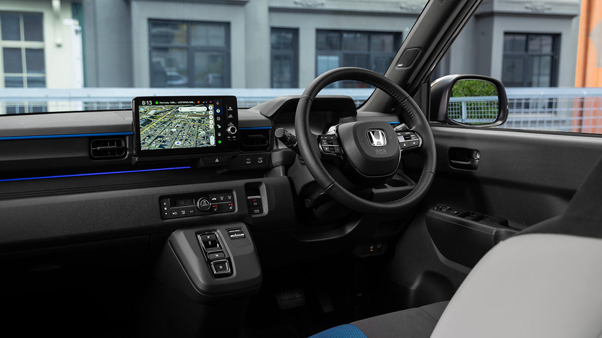 Dashboard of Honda Super-One EV with small central screen, retro-looking climate controls and large buttons on console.