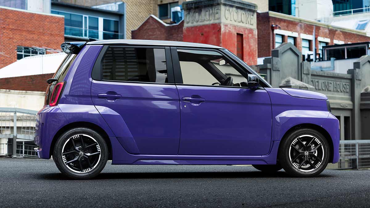 Side profile shot of purple Honda Super-One EV parked in inner-city location with heritage buildings.