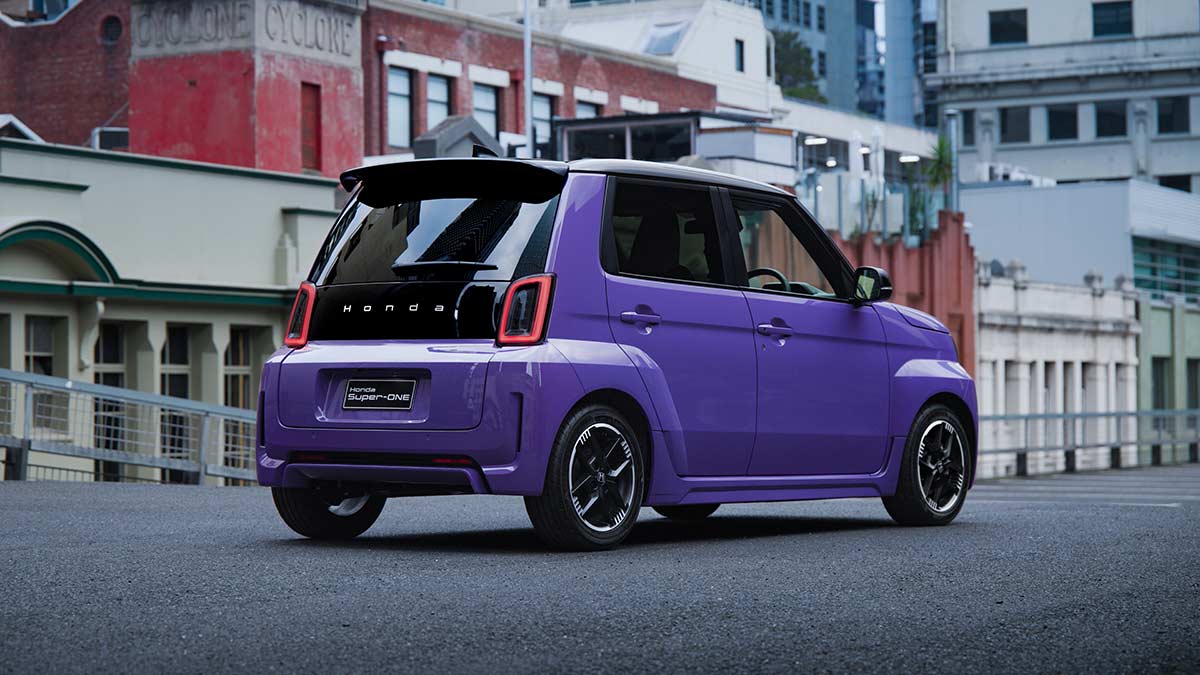 Rear three-quarter view of purple Honda Super-One EV parked in inner-city location with heritage buildings.