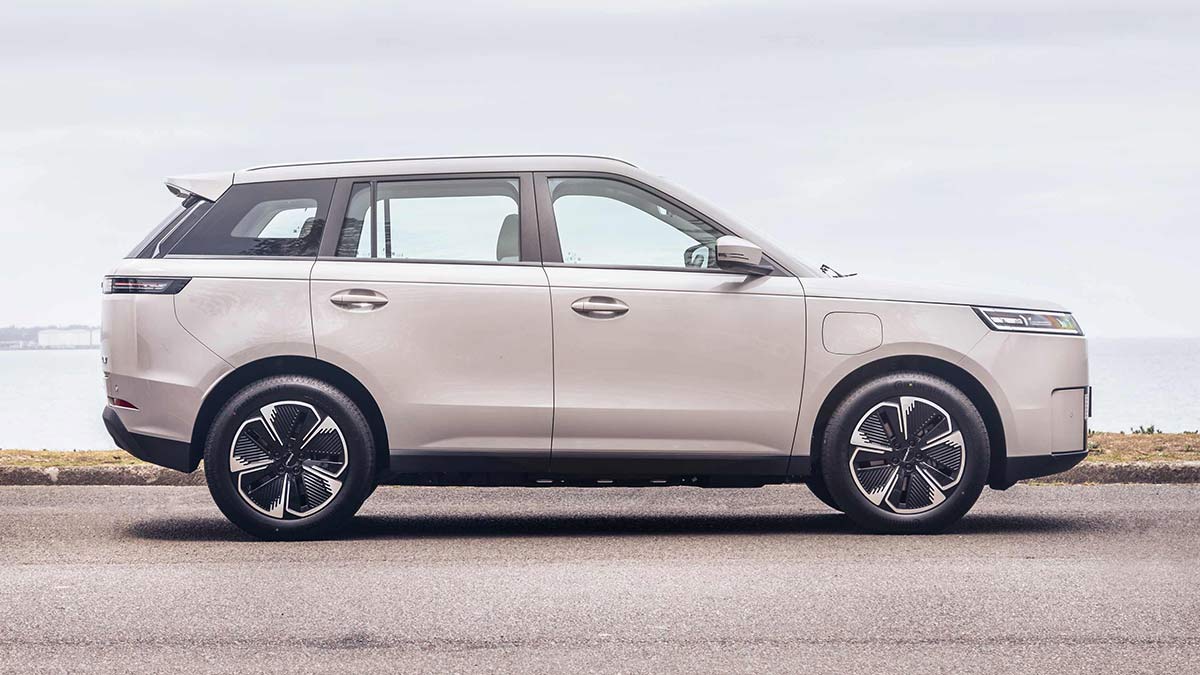 Side-on view of Jaecoo J5 EV small SUV at beachfront carpark.