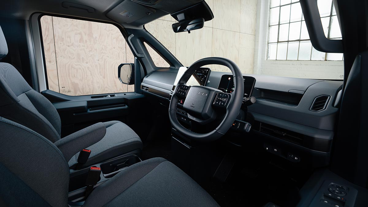 Kia PV5 Cargo electric van cabin with twin bucket seats with grey dashboard trim with dual digital screens.
