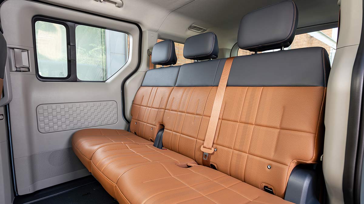 Second row in Kia PV5 Passenger EV people-mover with tan and grey seat trim.