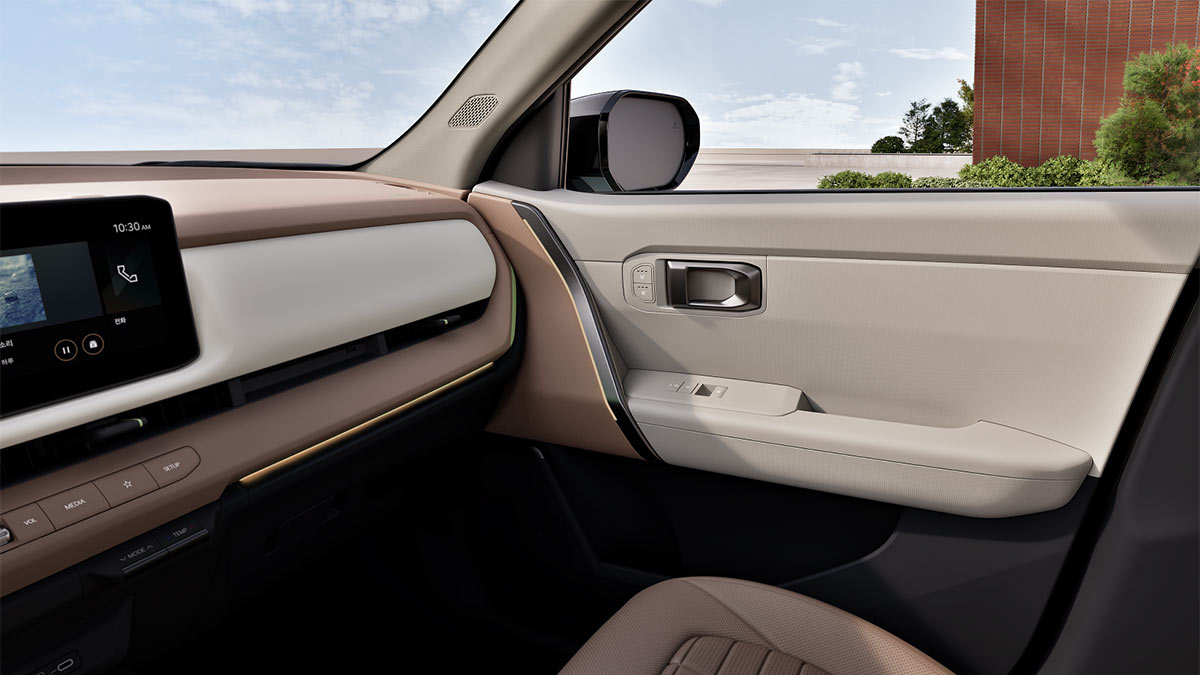 Dual-tone cream/flesh-coloured trim on front right door of Kia Seltos SUV with metallic trim highlights.