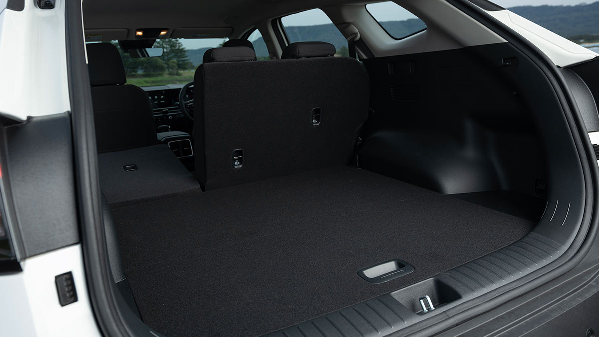 Rear of Kia Sportage S petrol model with tailgate open and view into boot and passenger area with seat folded down