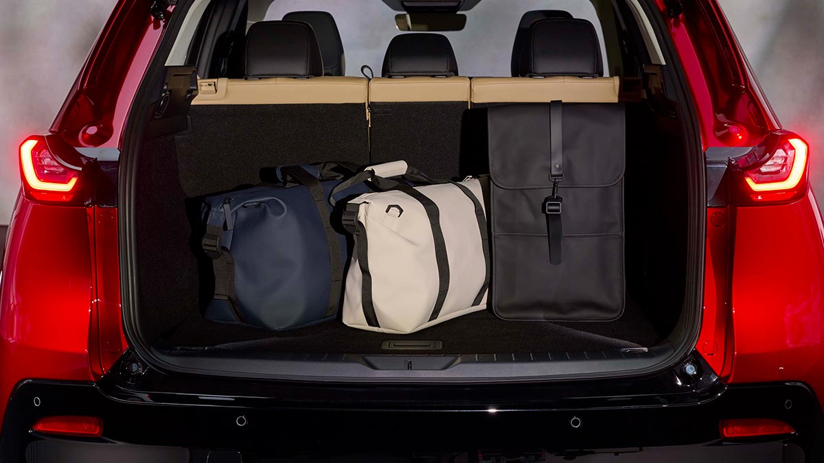 Cargo area of red Mazda CX-5 SUV with bags and accessories.