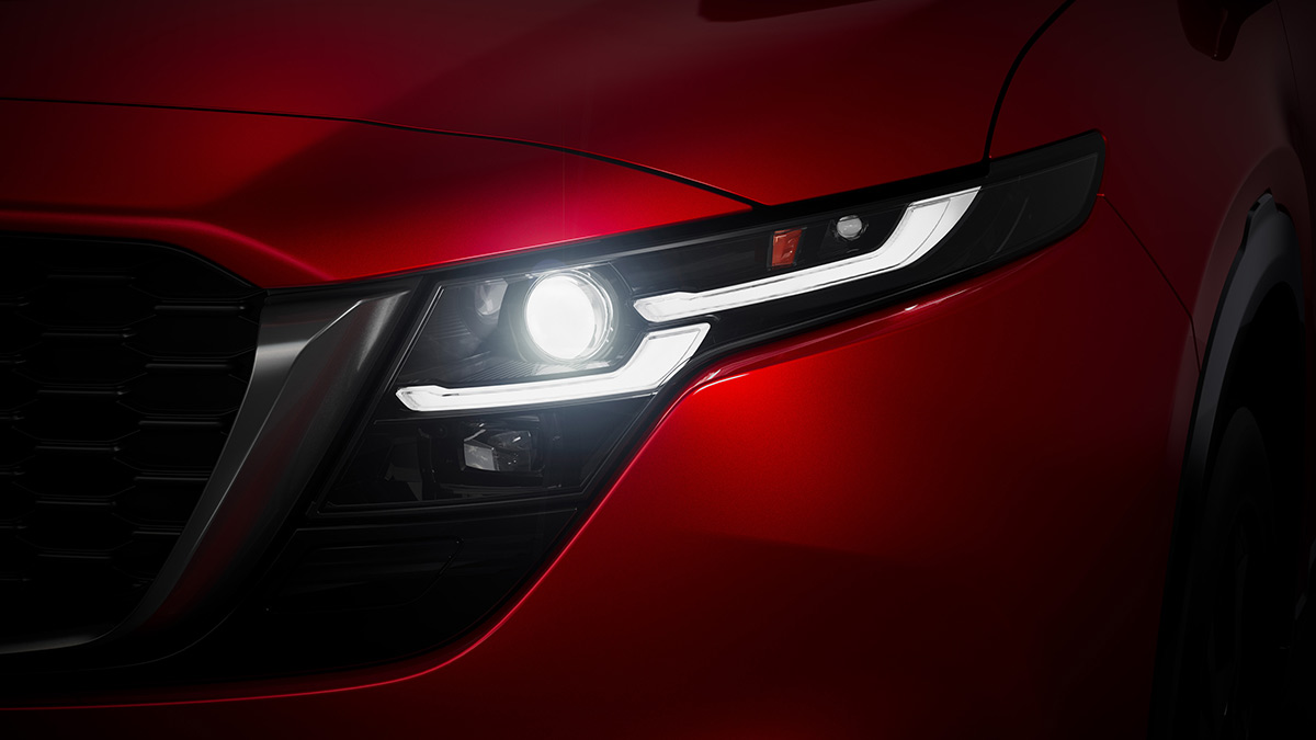 Close-up of narrow headlight cluster on red Mazda CX-5 medium SUV.