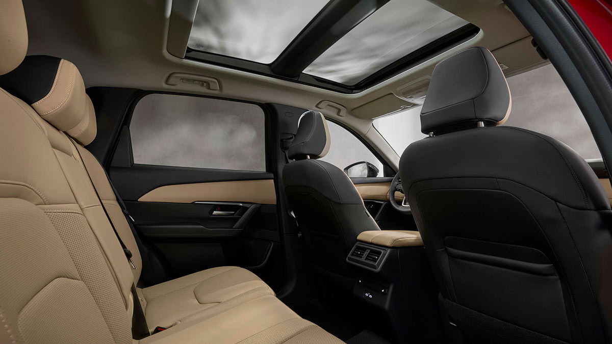 Rear seats of red Mazda CX-5 SUV with tan leather seats and panoramic sunroof.