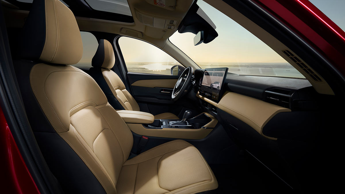 Front seats of Mazda CX-5 seen from front passenger door showing tan leather seats, large central console and centre touchscreen display.