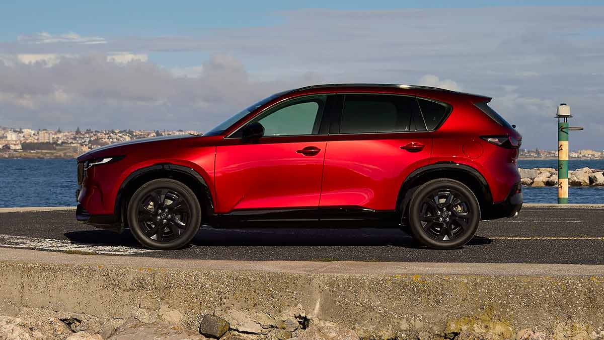 Side view of red Mazda CX-5 medium SUV parked at coastal carpark.