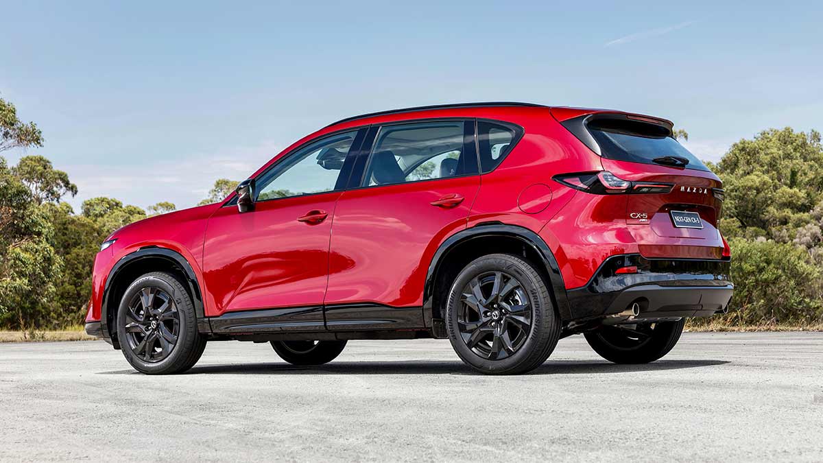 Rear three-quarter view of red Mazda CX-5 Akera SUV with black 19-inch alloy wheels, parked at bushy Lang Lang proving ground in Victoria.