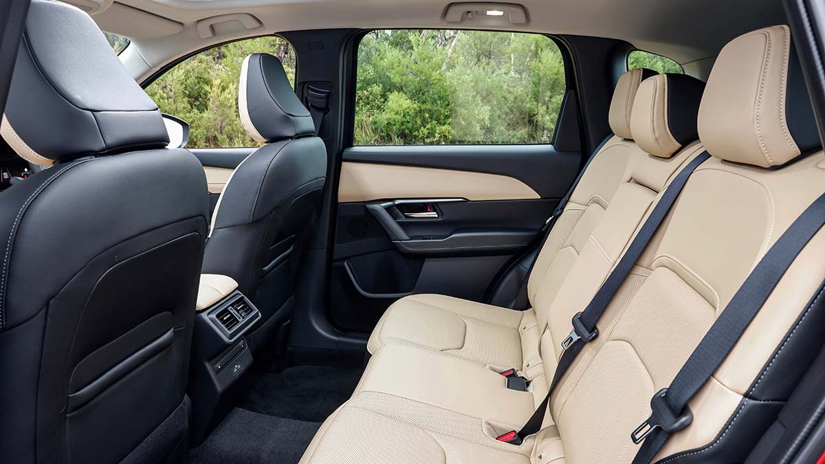 Roomy back seat of Mazda CX-5 Akera medium SUV with tan leather upholstery and dark grey front seatbacks.