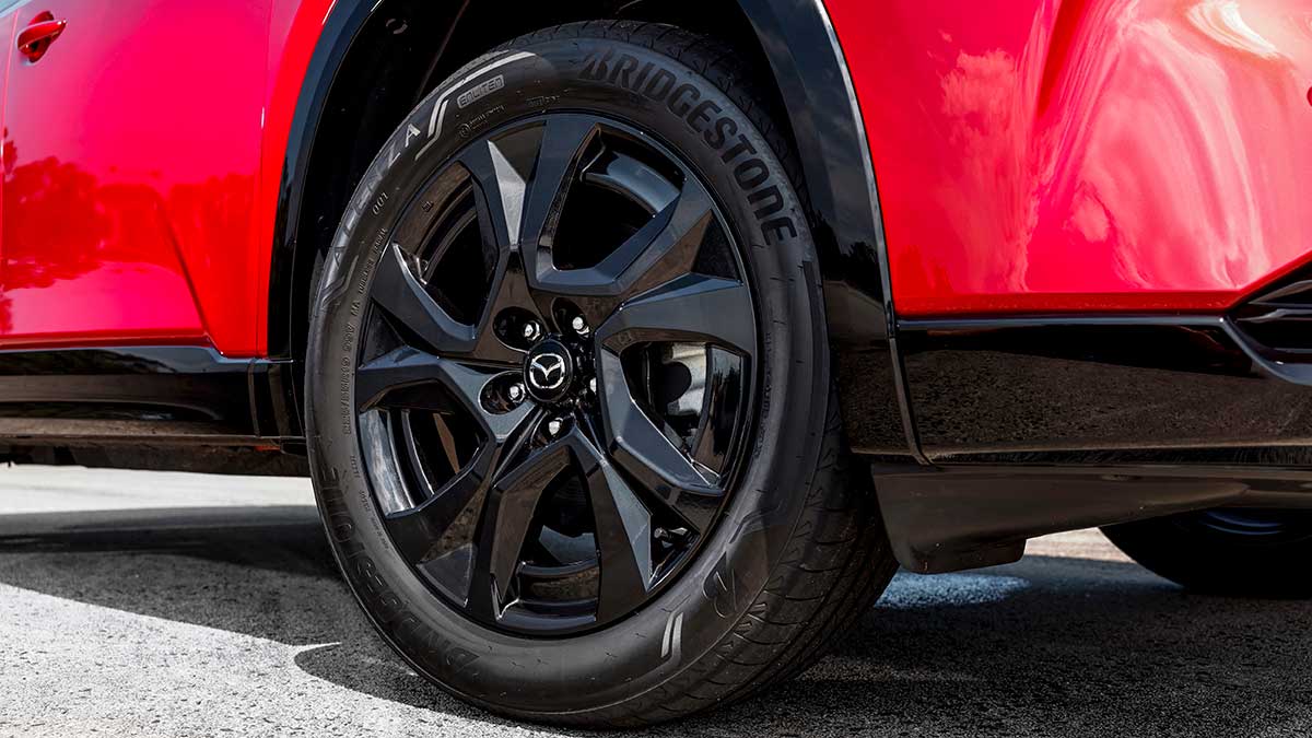 Rear left black 19-inch alloy wheel and Bridgestone tyre on red Mazda CX-5 Akera SUV.