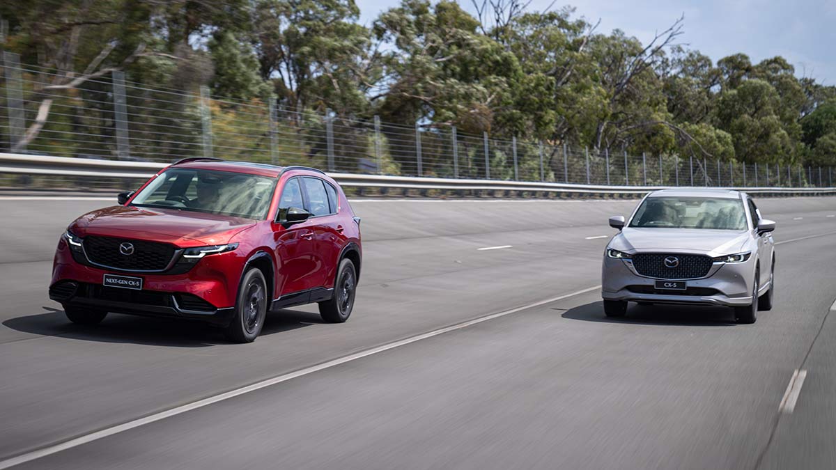 Red Gen 3 Mazda CX-5 SUV driving ahead of silver Gen 2 CX-5 on high-speed circuit at Lang Lang proving ground in Victoria.
