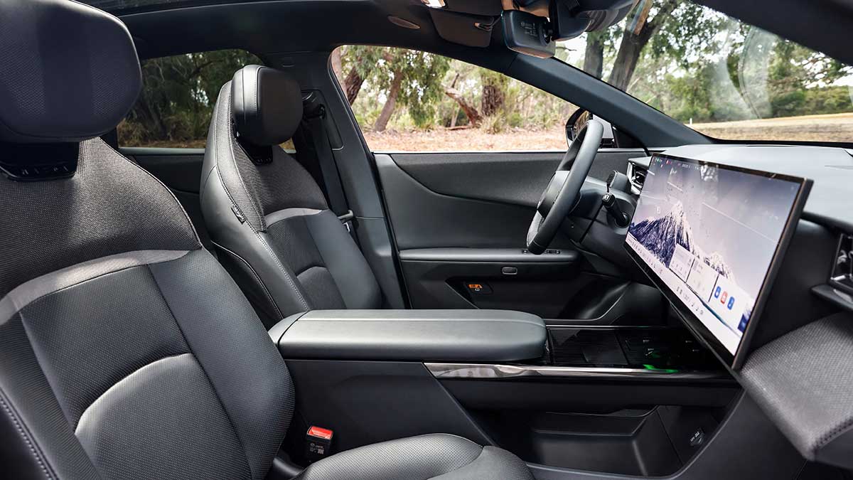 View from front passenger’s door inside Mazda CX-6e SUV with oversized central touchscreen and grey synthetic leather seats.