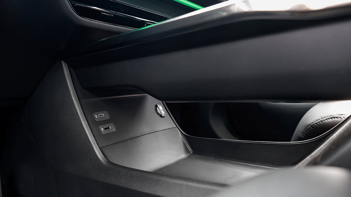 View of lower centre console in Mazda CX-6e SUV with storage area and charging points. 