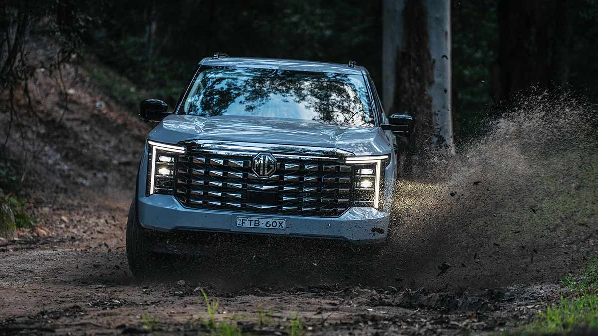 Frontal shot of blue MG U9 ute flicking up mud on off-road track.