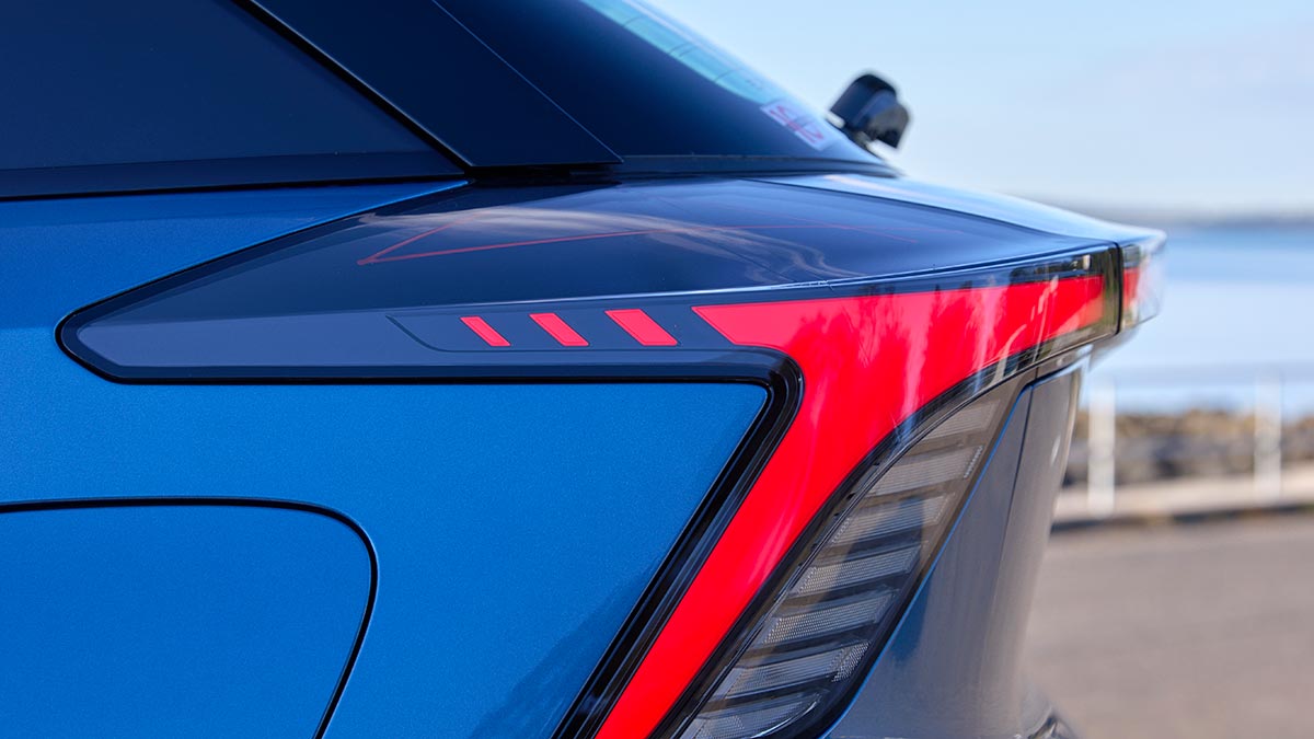 Red LED lights in angular tail-light cluster at right rear of blue MG4 electric hatchback.