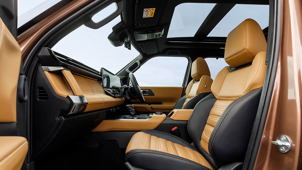 View of Mitsubishi Pajero cockpit from front passenger's door with tan and black trim and panoramic sunroof.